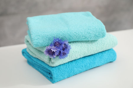 Stack of colorful towels and flowers on white table, closeupの写真素材