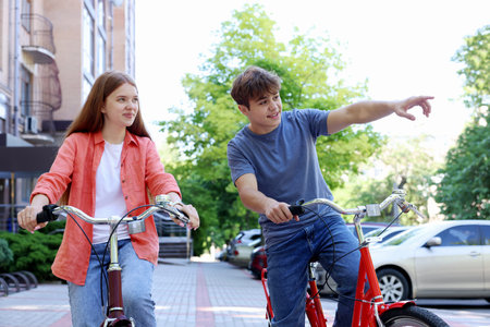 Teenage girl and boy riding bicycles on city street