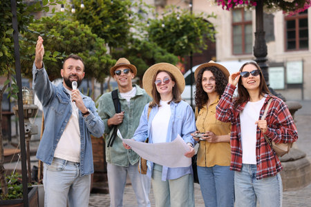 Guide with microphone and group of tourists on city street during excursionの写真素材