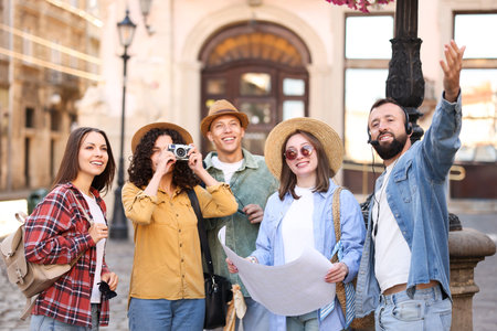 Guide with headset and group of tourists on city street during excursionの写真素材