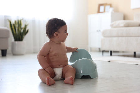 Cute little baby with potty on floor at homeの写真素材