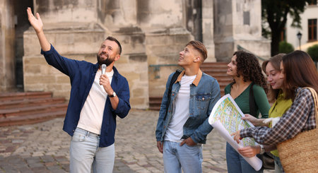 Guide with microphone and group of tourists on city street during excursionの写真素材