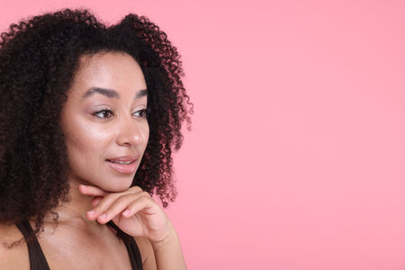 Beautiful Brazilian woman with healthy skin on pink background. Space for text