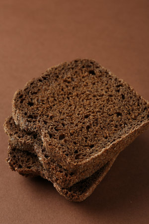 Pieces of fresh rye bread on brown background, closeup