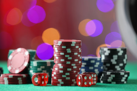 Casino chips and dice on green table against blurred lights, closeupの写真素材