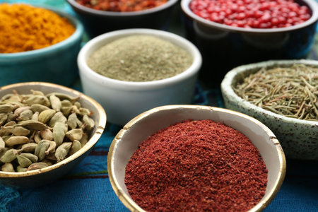 Different aromatic spices on blue tablecloth, closeup