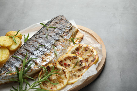 Homemade seafood dish. Tasty roasted mackerel with spices and potatoes on gray table, closeup. Space...