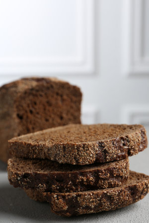 Pieces of fresh rye bread on light gray textured table, closeup