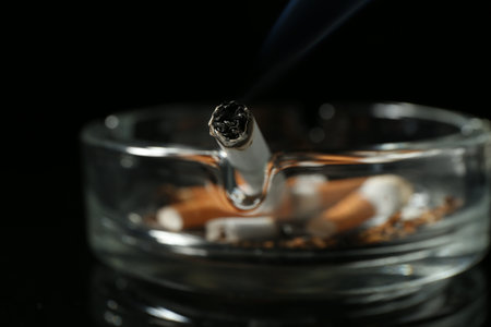 Cigarette butts in ashtray on black background, closeupの写真素材