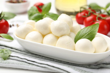 Tasty mozzarella cheese, tomatoes, basil and spices on table, closeup