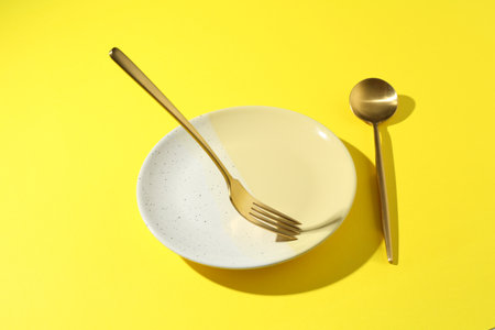 Stylish plate and cutlery on yellow background, above viewの写真素材