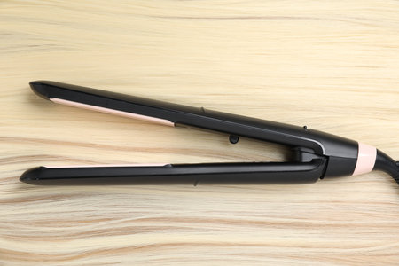 Modern flat iron on shiny blonde hair, top view