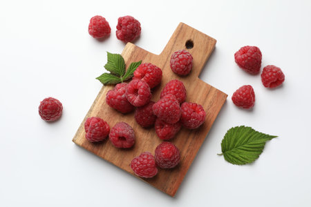 Fresh ripe raspberries and leaves on white background, flat lay