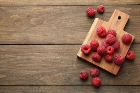 Tasty fresh ripe raspberries on wooden table, flat lay. Space for text