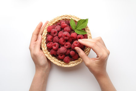Woman with tasty fresh ripe raspberries and leaves on white background, top view