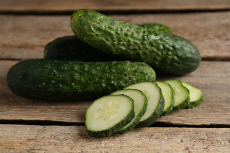 Whole and cut cucumbers on wooden table, closeupの写真素材