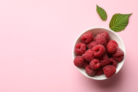 Tasty fresh ripe raspberries and leaves on pink background, flat lay. Space for text
