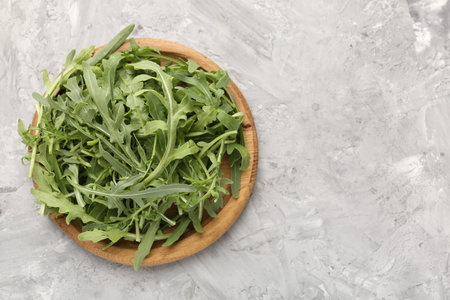 Fresh ripe green arugula leaves on grey table, top view. Space for text