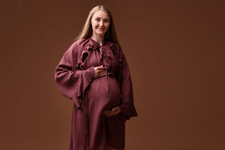 Beautiful pregnant woman in dress on brown background