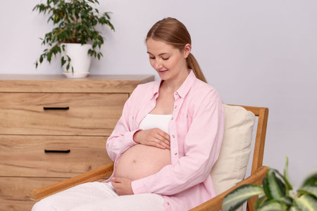 Beautiful pregnant woman in armchair at home