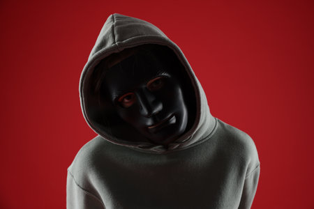 Anonymity. Woman wearing mask on red backgroundの写真素材