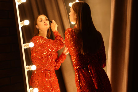 Beautiful woman applying mascara while getting ready near mirror indoorsの写真素材