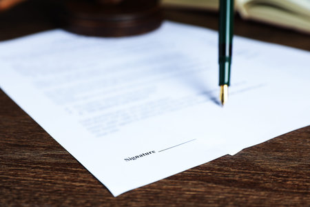Signing notary document with fountain pen at wooden table, selective focus
