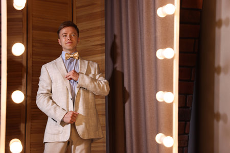 Handsome man getting ready near mirror indoors
