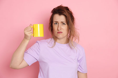 Woman with cup of coffee on pink background
