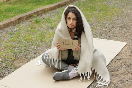 Homeless woman with sign Help on carton in park