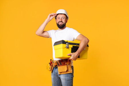 Professional repairman with tool box on orange background