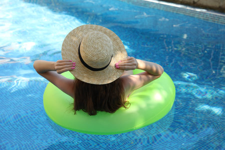 Girl on inflatable ring in swimming pool, back view