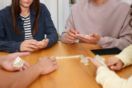 Friends playing dominoes at wooden table indoors, closeupの写真素材