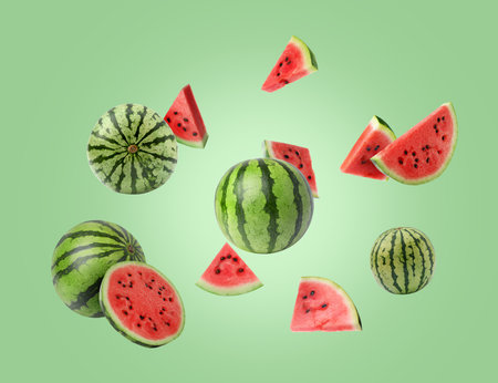 Fresh watermelons in air against light green background