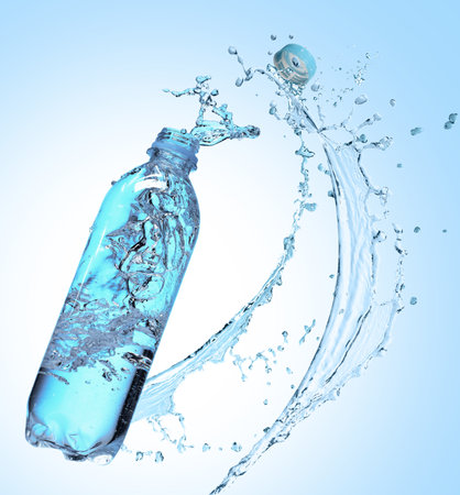 Soda water in bottle and splash against light blue backgroundの写真素材