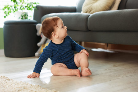 Cute little baby sitting on floor at home