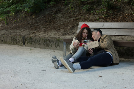 Homeless people with sign Help near bench in park, space for textの写真素材