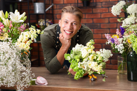 Professional florist with bouquet of flowers at wooden table in shopの写真素材