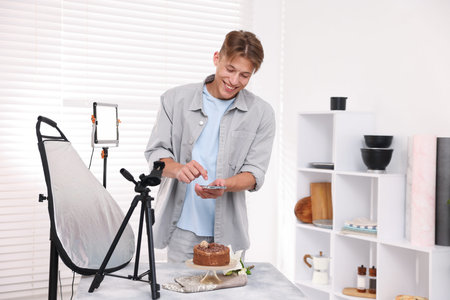 Man taking picture of chocolate cake in studio. Professional food photography