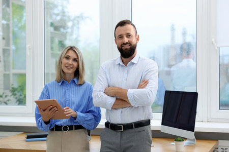 Portrait of smiling business partners with tablet in officeの写真素材