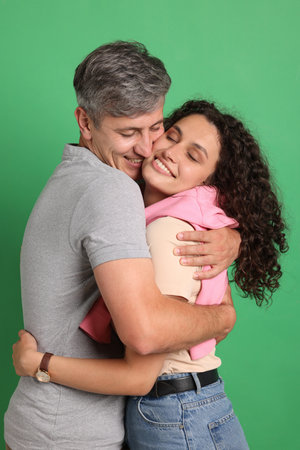 Happy friends hugging each other on green backgroundの写真素材