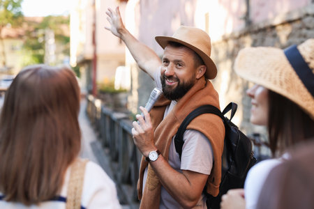 Guide with microphone and tourists on city street during excursionの写真素材