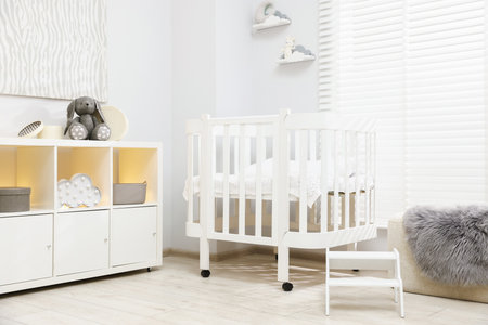 Beautiful baby room interior with stylish crib, other furniture and toysの写真素材
