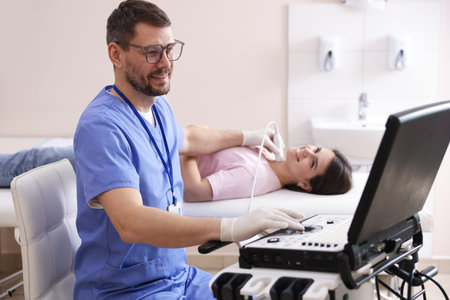 Sonographer conducting ultrasound examination of woman's thyroid gland in clinic