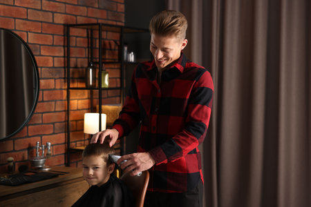 Professional barber working with little boy in barbershopの写真素材