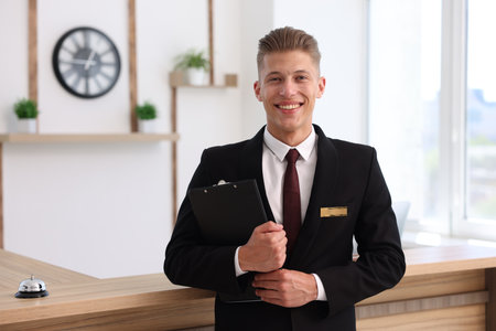 Portrait of smiling receptionist with clipboard in hotelの写真素材
