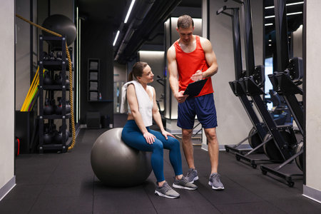 Young woman with professional personal trainer in gym