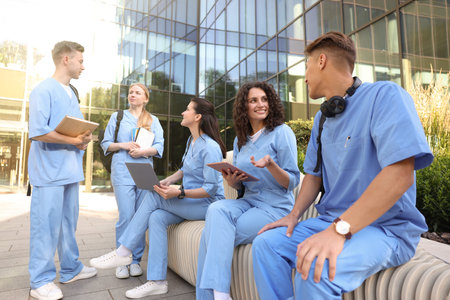 Group of medical students in uniforms studying together near building outdoors