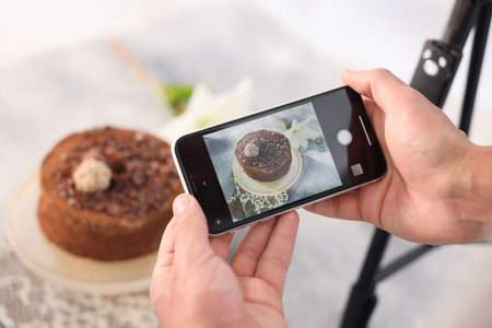 Man taking picture of chocolate cake in studio, selective focus. Professional food photography