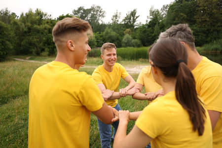 Team building. Group of happy people joining hands outdoors